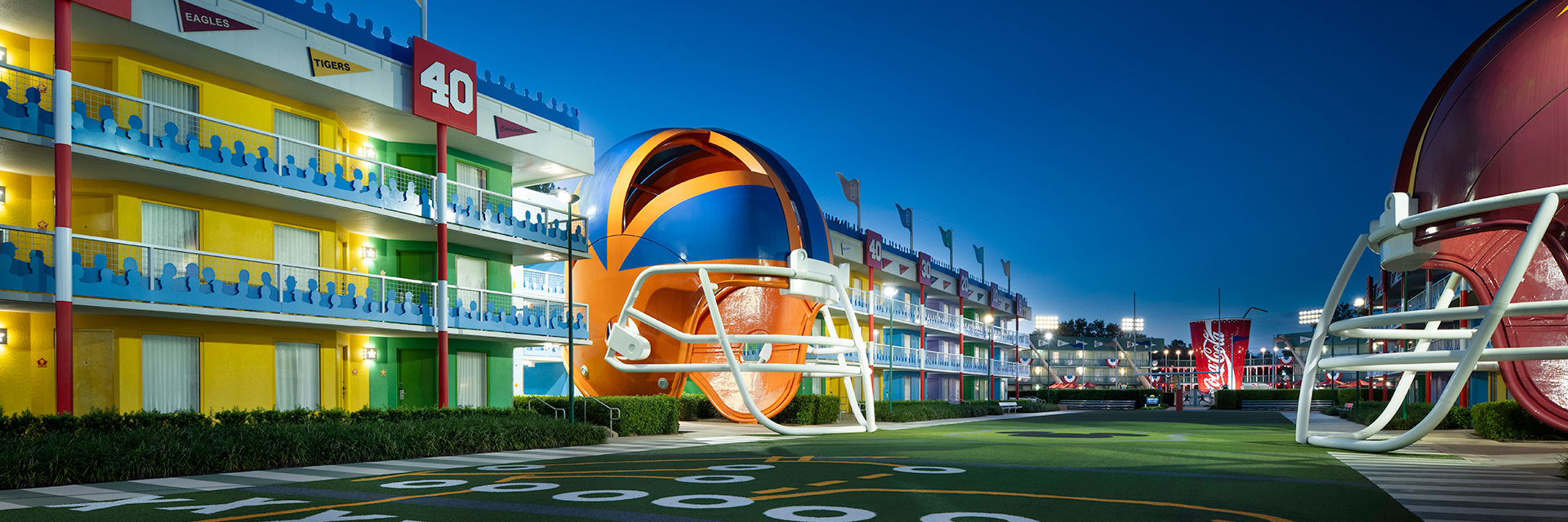 Football-themed hotel courtyard at night with oversized helmets and yard-line markings.