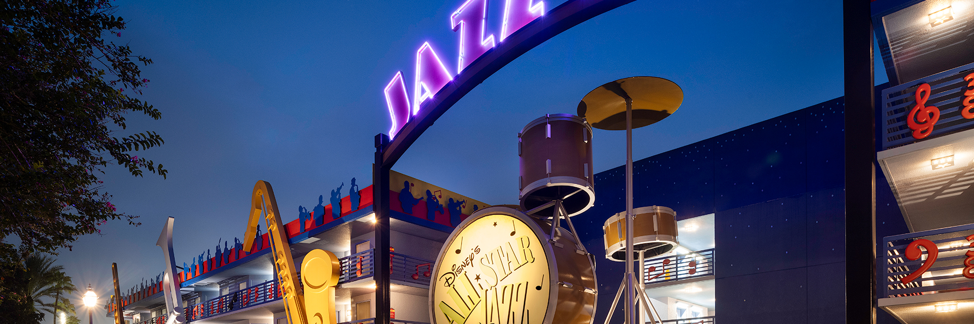 Neon Jazz Inn sign and giant instruments at Disney’s All-Star Music Resort at night.