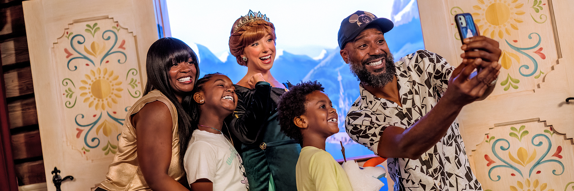 Family of four posing for a selfie with Princess Anna inside a colorful, storybook-style room.